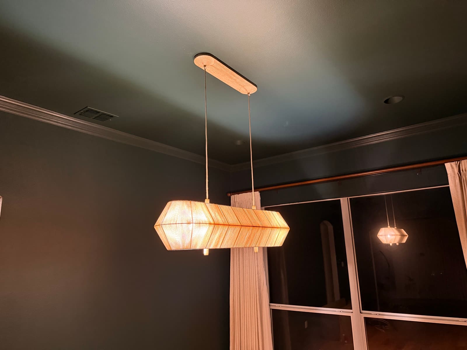 Linear woven pendant fixture installed on a dark-painted ceiling