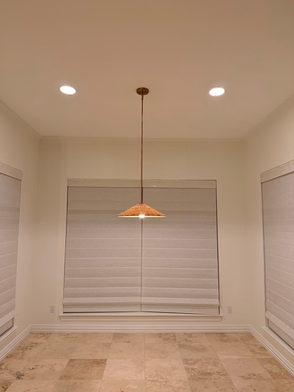Rattan pendant light installed over a dining nook, with recessed lighting